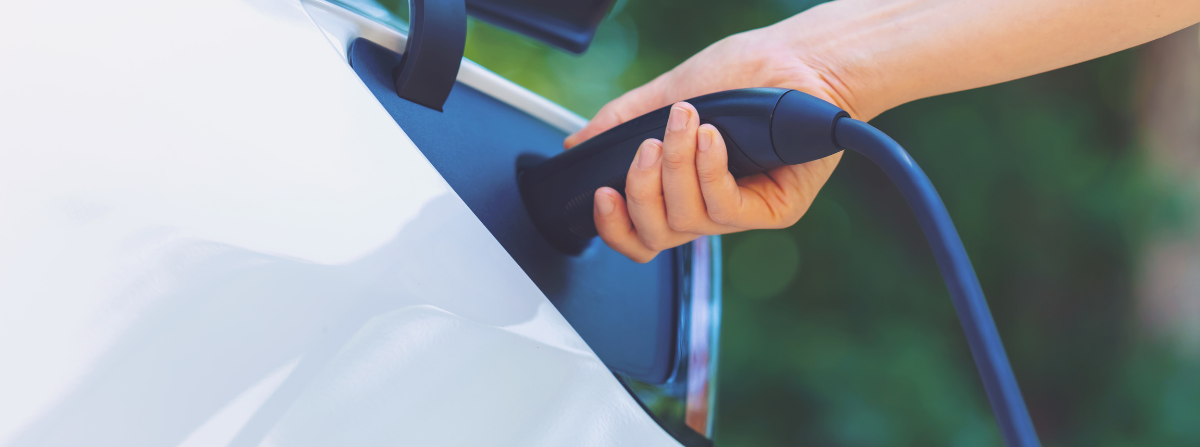 Person putting a charger for an electric vehicle into the charging outlet of the vehicle