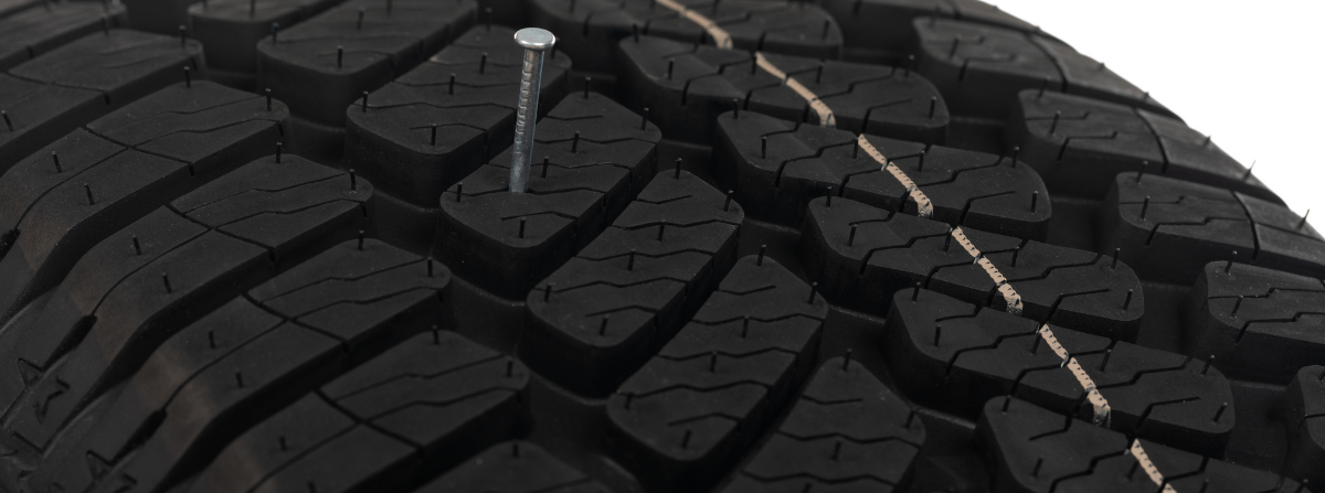 Photo of a nail stuck in the middle of a car tire tread