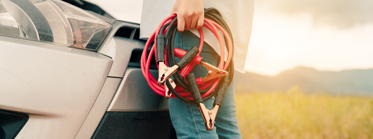 Person holding car battery jumper cables