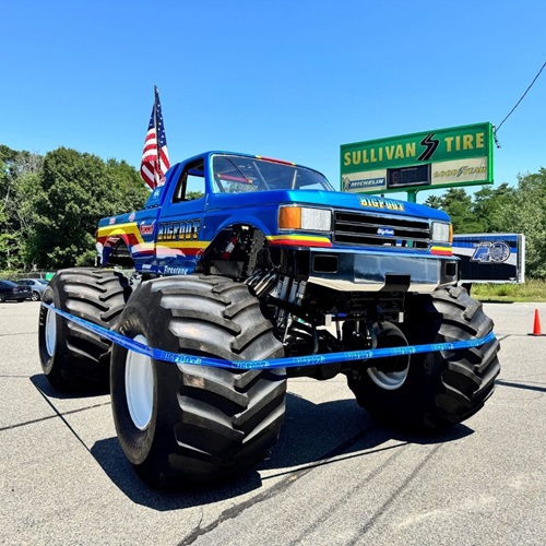 The Bigfoot monster truck in front of a Sullivan Tire roadside sign