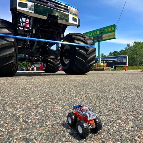 A small Hot Wheels toy Bigfoot Truck in front of the actual thing demonstrating the scale