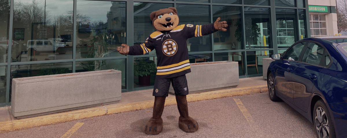 Blades mascot posing open armed in front of a Sullivan Tire storefront