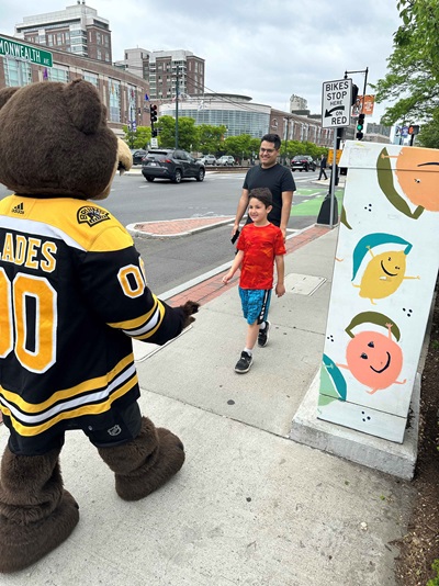 Blades the mascot greeting a child and their father outside of the Comm Ave Sullivan Tire