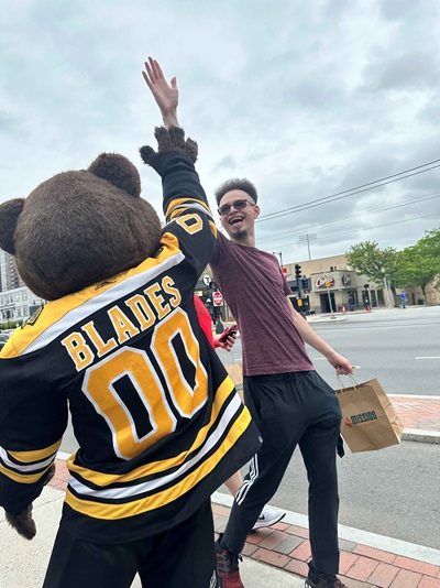 Blades giving a big high five to a tall passerby in sunglasses