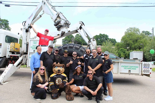 Sullivan Tire Dover staff posing in front of the Sullivan Tire Boom Truck with Big League Brian and Blades the Bruins mascot