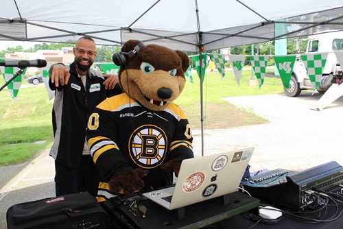 Sullivan Tire employee and Blades the bear posing behind the DJ booth