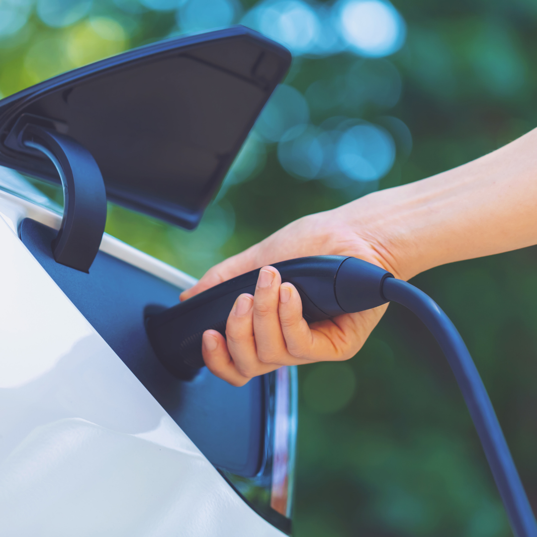 Person putting a charger for an electric vehicle into the charging outlet of the vehicle