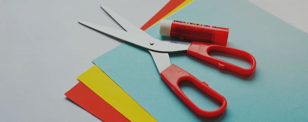 Large banner image of colored paper with scissors and a glue stick on it