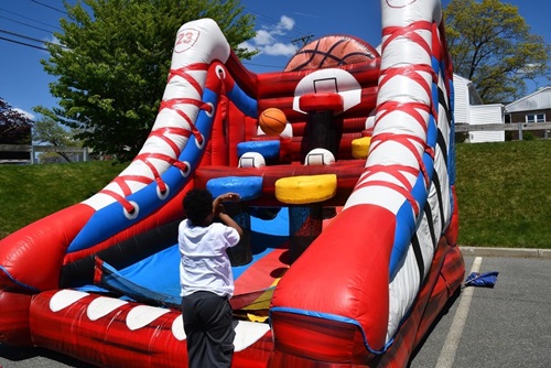 A child playing basketball with an inflatable bounce house hoop set up.