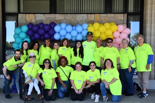 Large group of volunteers gathered in a group photo in front of a balloon arch 